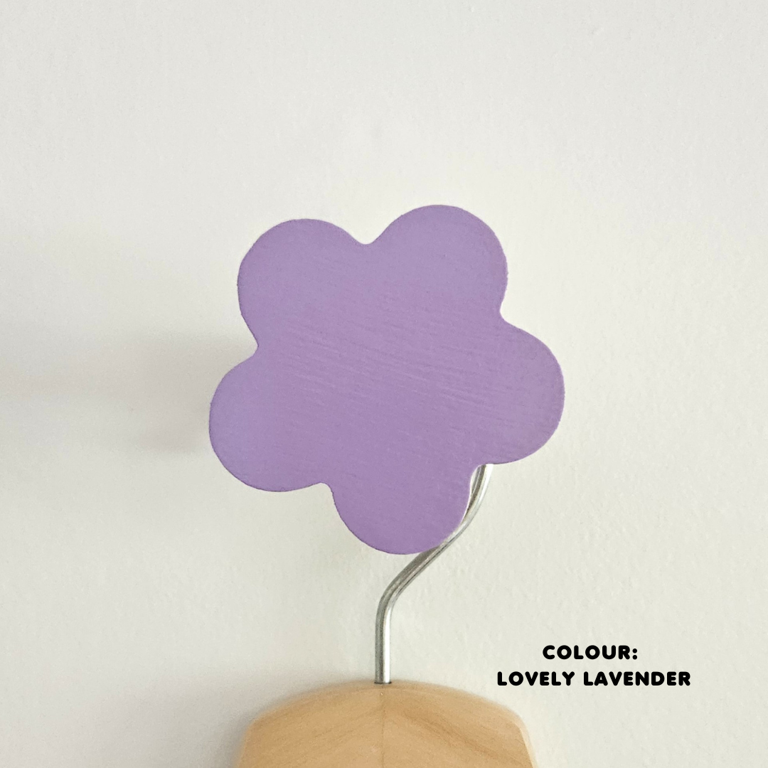 A purple flower-shaped wall hook mounted on a white wall, with the text 'COLOUR: Lovely Lavender' at the bottom.