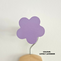 A purple flower-shaped wall hook mounted on a white wall, with the text 'COLOUR: Lovely Lavender' at the bottom.