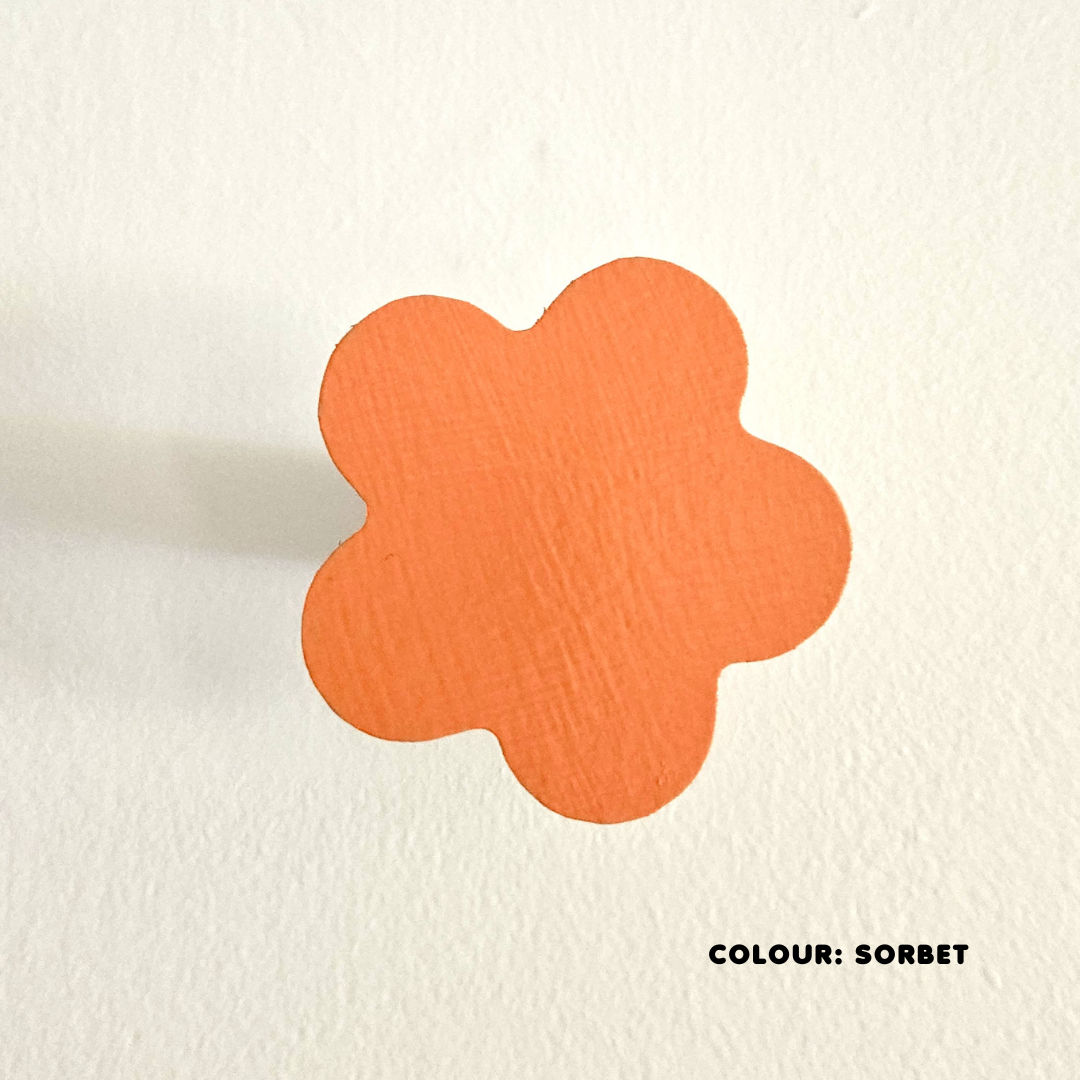An orange coloured flower-shaped wall hook mounted on a white wall, with the text 'COLOUR: Sorbet' at the bottom.